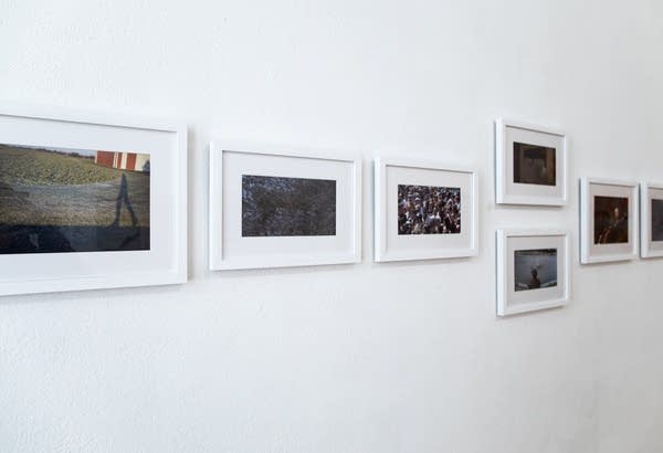 A series of photographs hangs on a white wall