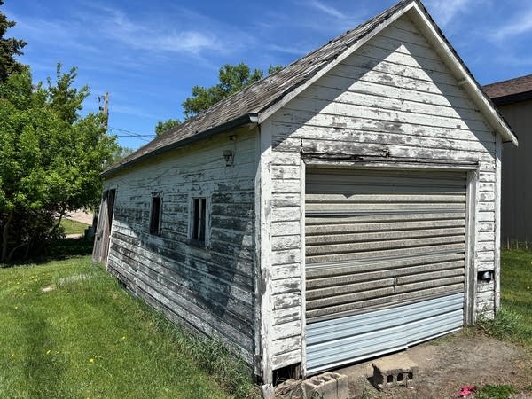 A weathered shed with a wall that is leaning.