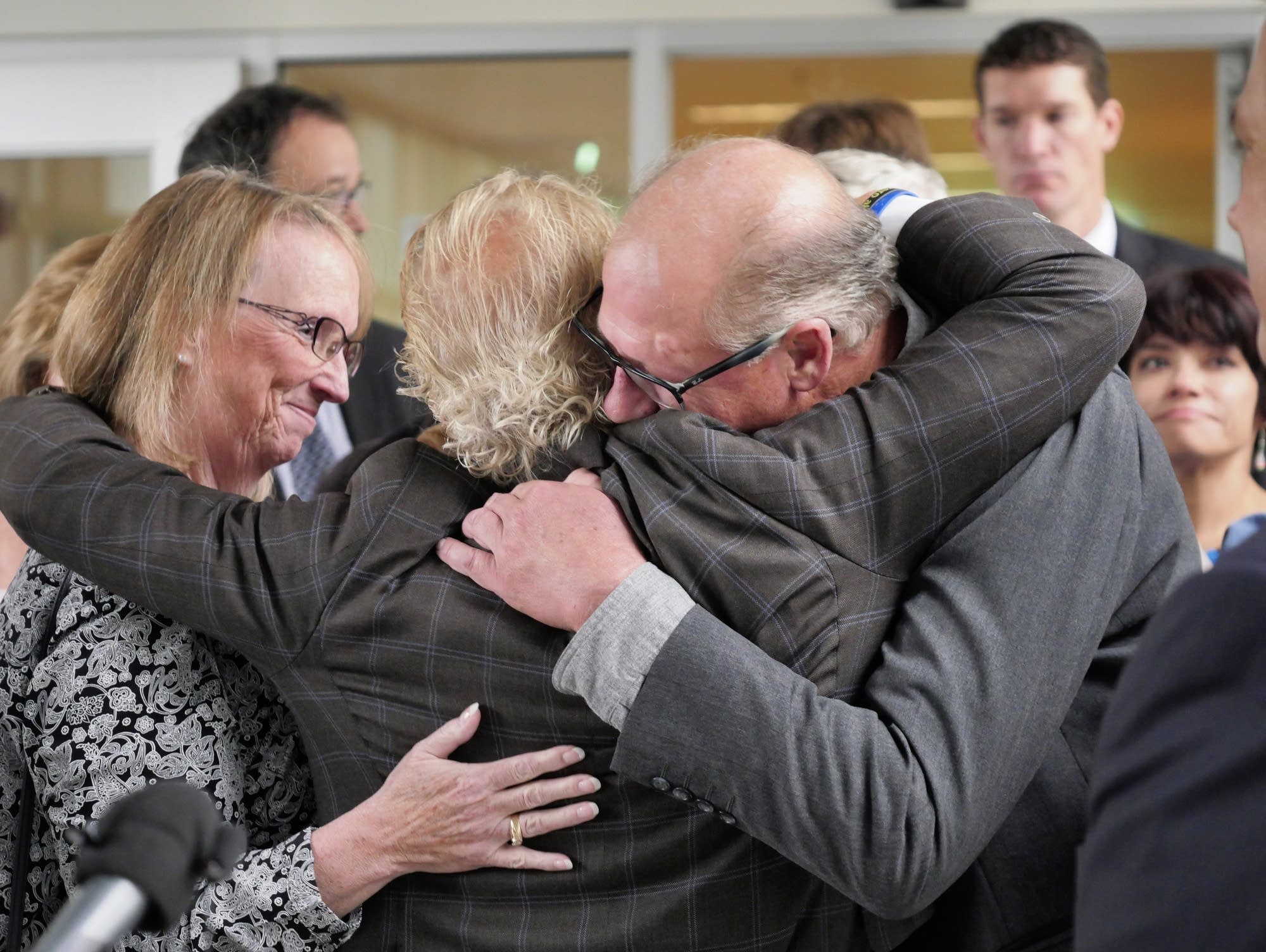 Victims' attorney Jeff Anderson, center, embraces his clients