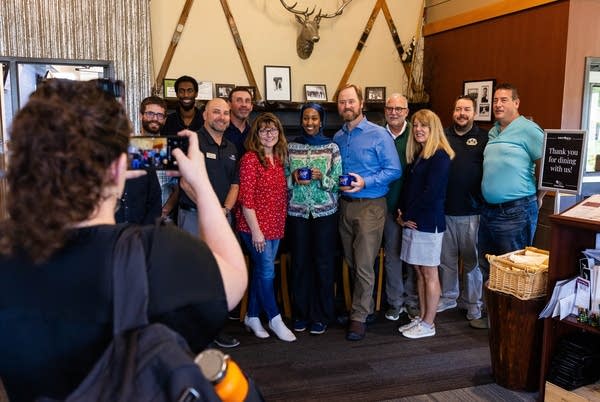 A group smiles and poses for a photo in a restaurant.