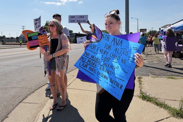 People hold signs on a street corner