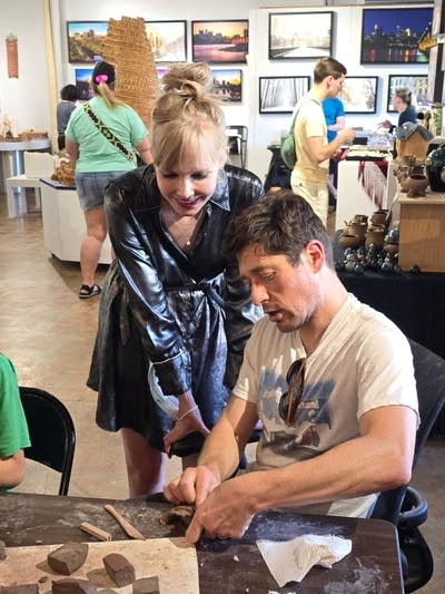 A woman helps a man with an art project.