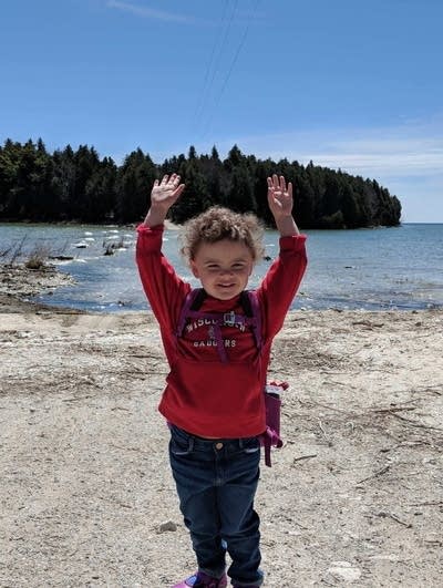 A young girl raises her hands 