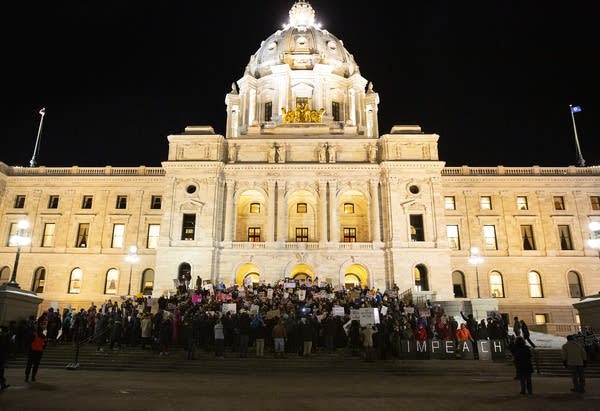 A crowd of people stand on the steps of the Capitol building. 