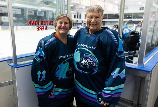 two people in hockey jerseys posing for photo