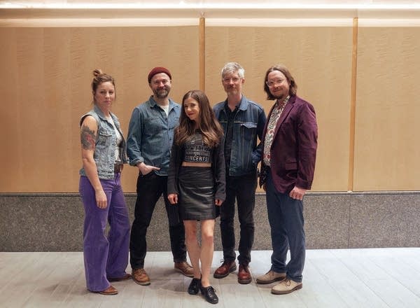 Five musicians stand together for a portrait