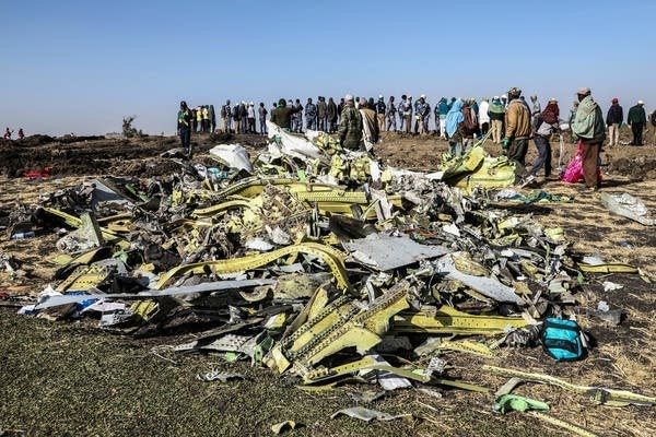 People stand near collected debris at the crash site of Ethiopia Airlines.