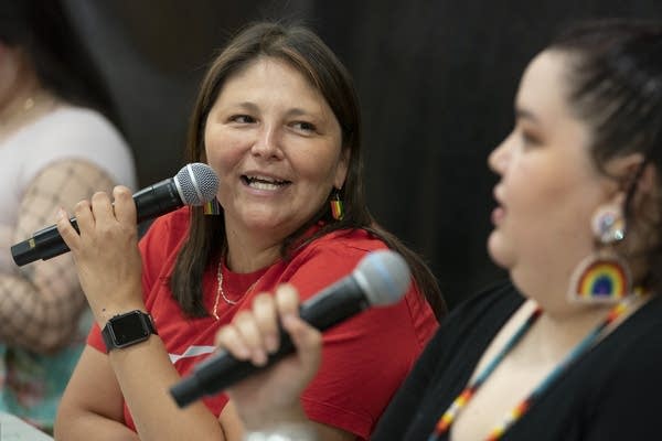 Two people speak while holding microphones.