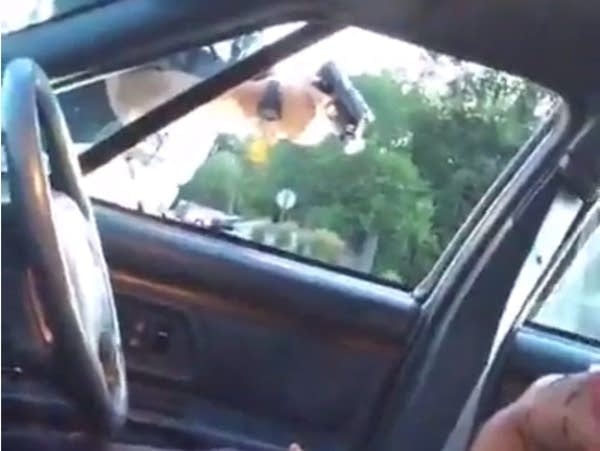 An officer points his gun into a vehicle.