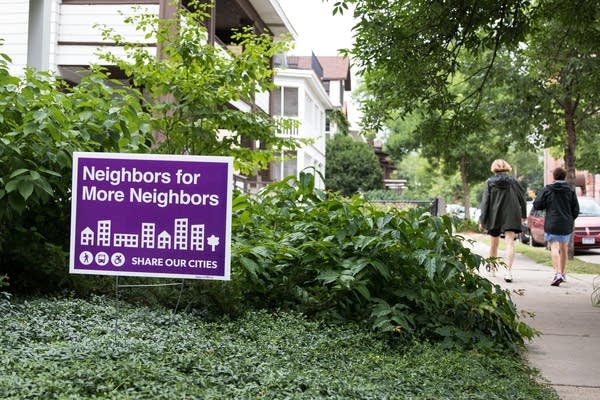 A Neighbors for More Neighbors sign sits in a front yard.