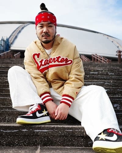 A man seated on the stairs outside a large stadium