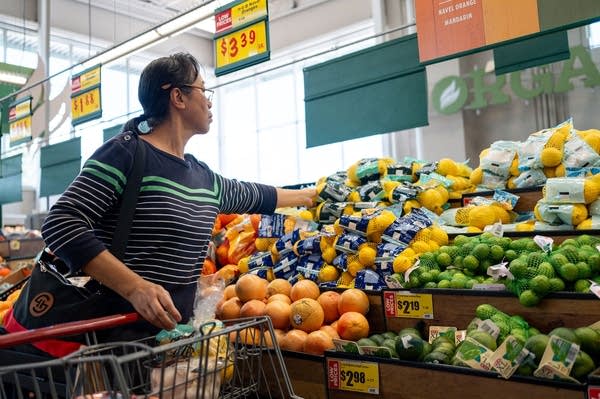A woman grabs a bag of lemons.