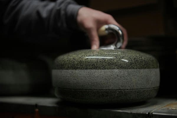 Close-up of a curling stone being placed on a table.