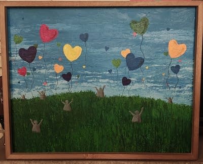 A painting shows heart shaped balloons rising into the sky with people in the grass below.