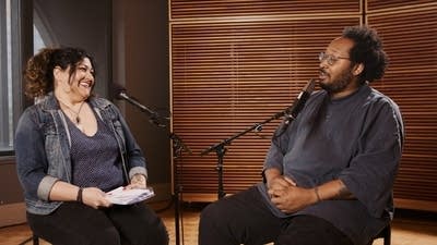 Two people have a conversation in a recording studio