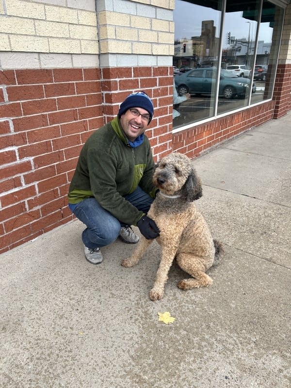 man posing outside for photo with dog