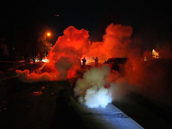 Law enforcement officers stand amid tear gas