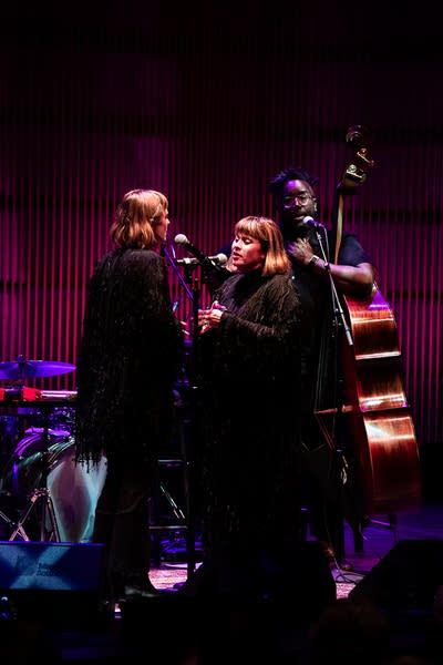 Three musicians performing together onstage in a concert hall