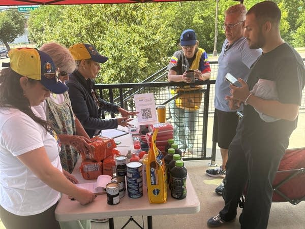 People track donations of food and supplies on a table outdoors