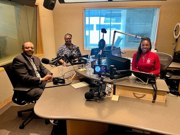 three people smiling in a broadcast studio