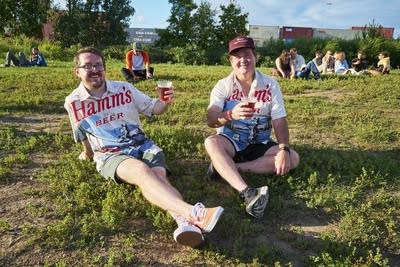 2 men in hamms shirts pose for a photo