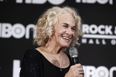 A woman smiles and speaks into a microphone