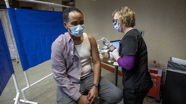 A man sits in a chair as he receives a vaccine. 