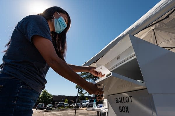 A person puts a ballot in a box. 