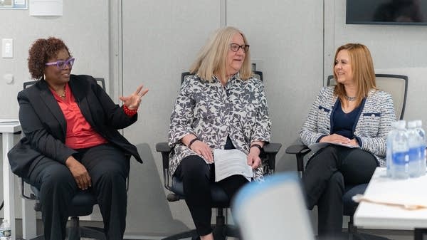 three women sit on chairs talking 