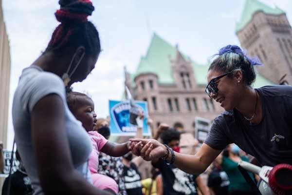 A woman holds hands and dances with a baby.