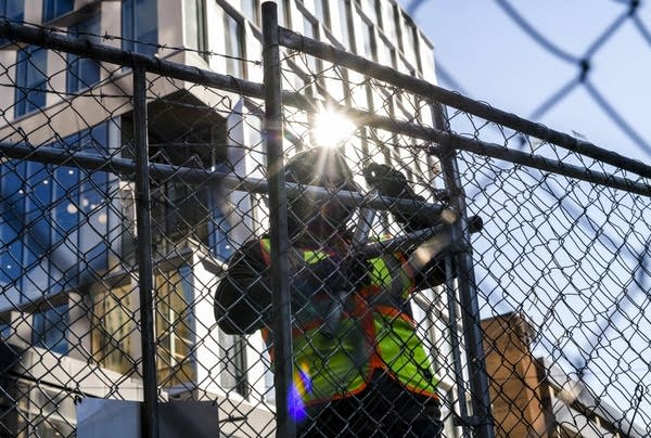 Crews install fencing outside a building. 