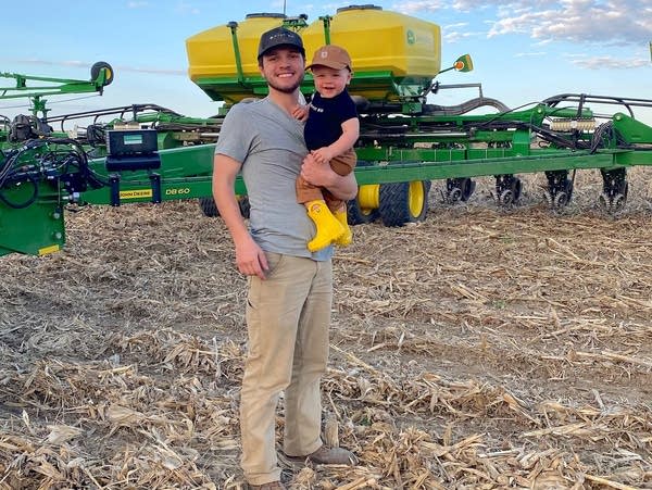 a man holding a small boy in a farm field