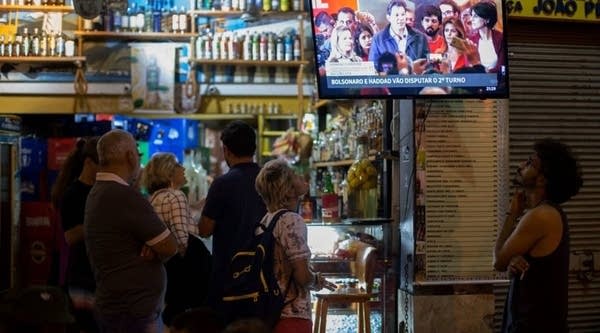 People watch Brazilian presidential candidate for the Worky Party (PT) Fernando Haddad's press conference on TV at a bar of Lapa neighborhood, in Rio de Janeiro, Brazil, October 07, 2018. - Polarizing far-right politician Jair Bolsonaro looked to be the big winner of a first-round presidential election in Brazil on Sunday, according to mostly complete results -- but a final victory in a run-off to be held in three weeks is far from assured.