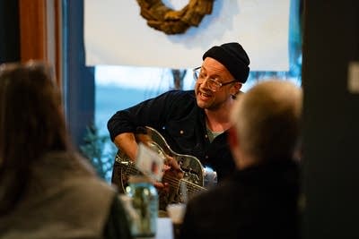 A musician plays guitar and sings in a coffeehouse