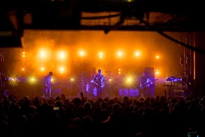 Band performing on stage with bright lights behind them
