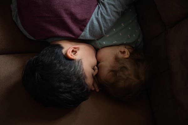 older child lays holding a younger baby