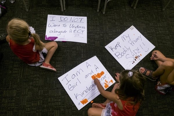 Children color on signs showing opposition to the transgender toolkit. 