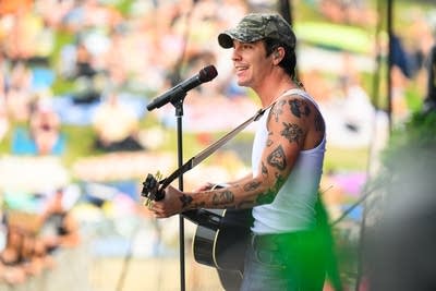 A musician sings and plays guitar on a large outdoor stage