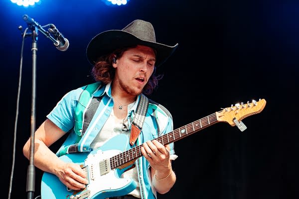A musician plays guitar on an outdoor stage