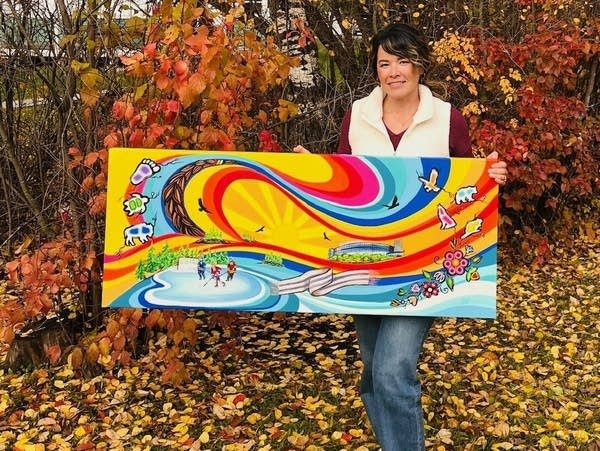 A woman holds a rendition of a mural.