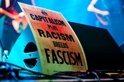 A poster reads: Capitalism plus racism breeds fascism