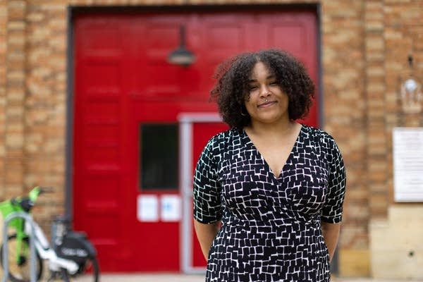 A woman poses for a photo in front of a red door