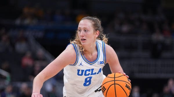 Medium shot of a UCLA women's basketball player holding the ball and looking to her right..