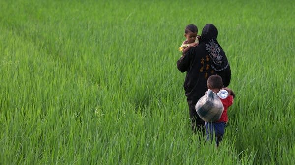 A Rohingya mother carries one child and leads another