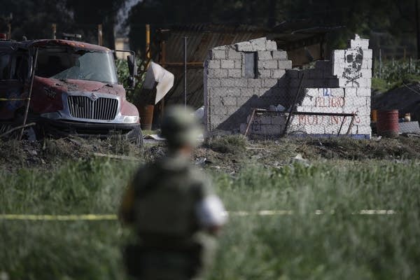 A soldier guards the perimeter around the wreckage.