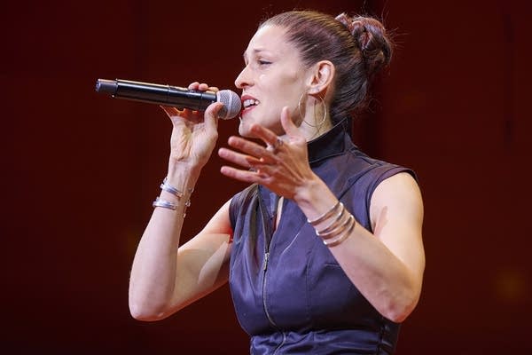 Dessa holds a microphone onstage at Orchestra Hall.
