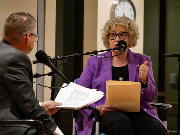 Two people sit on a stage to talk.