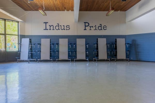 A view of a cafeteria with folded tables. The wall reads "Indus Pride."