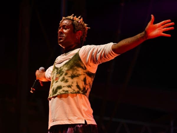 A singer holds their arms out wide