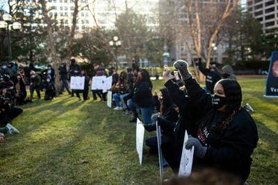 People kneel in protest near a press conference. 